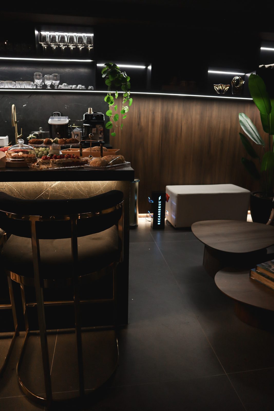 Canto de descanso do Bio Lounge Club com banquetas e placa Recarregue